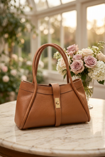 Cargar imagen en el visor de la galería, Bolso camel sobre una mesa de mármol con un fondo romántico de rosas y jardín desenfocado
