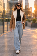 Cargar imagen en el visor de la galería, Modelo urbana con el chaquetón camel abierto, largo justo por debajo de la cadera, en una ciudad moderna al atardecer
